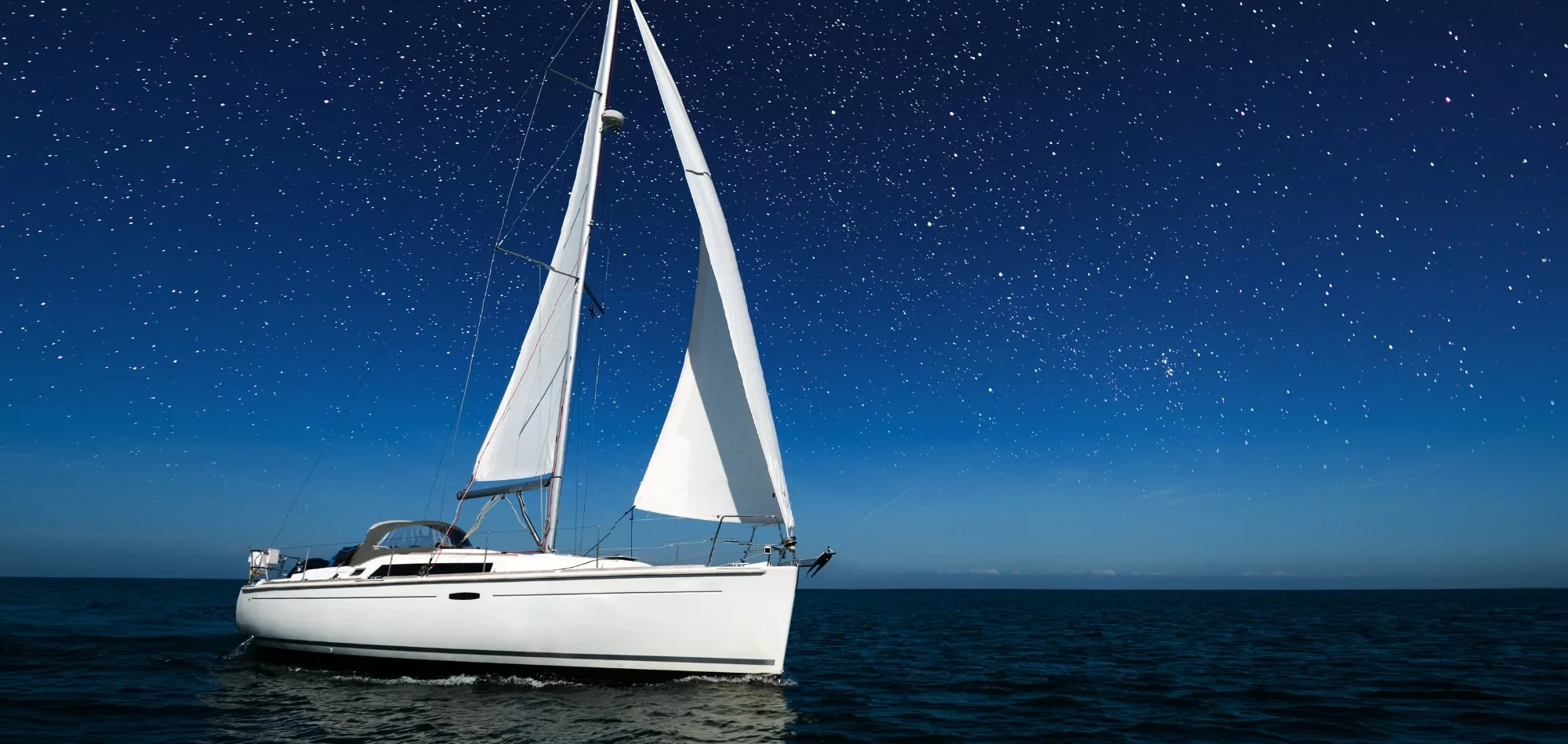 A sailboat on the open seas under the stars, symbolizing how Velorum Wealth Management can act as you navigator and steer you to calm waters.